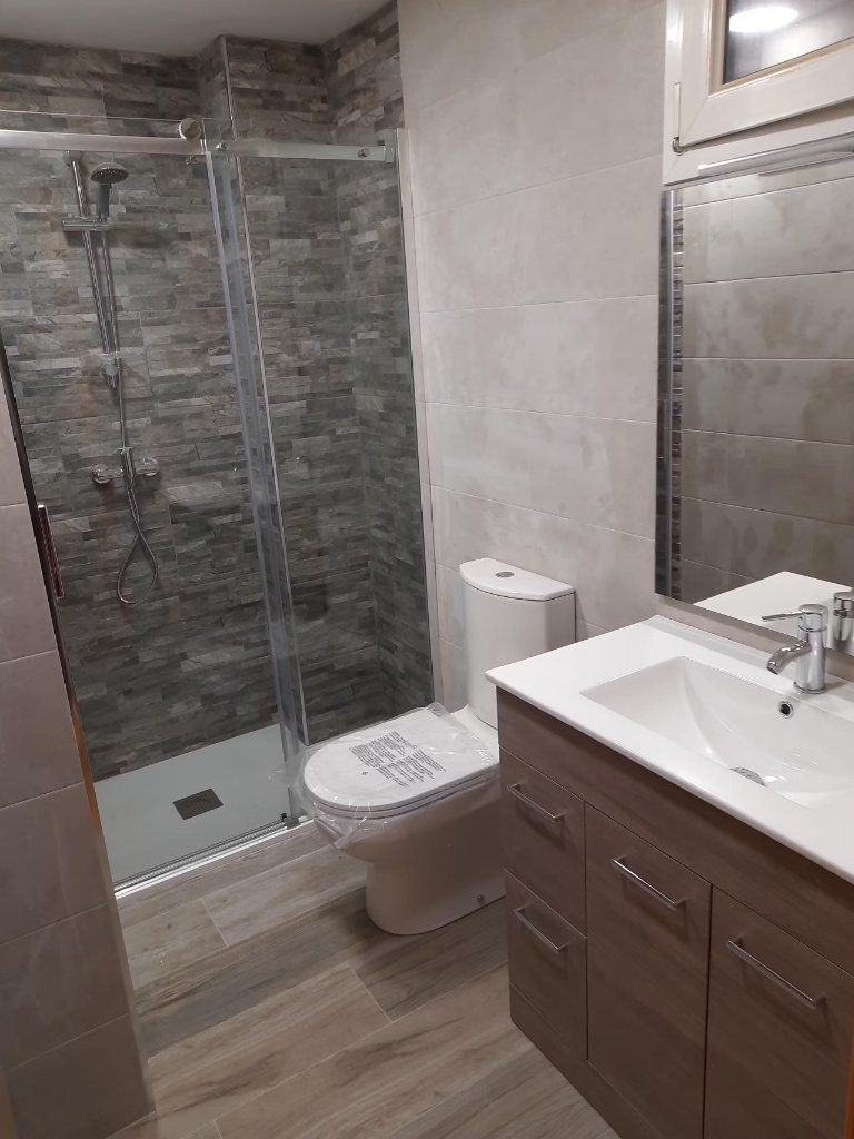 Baño con ducha en piedra y mueble de lavabo en madera