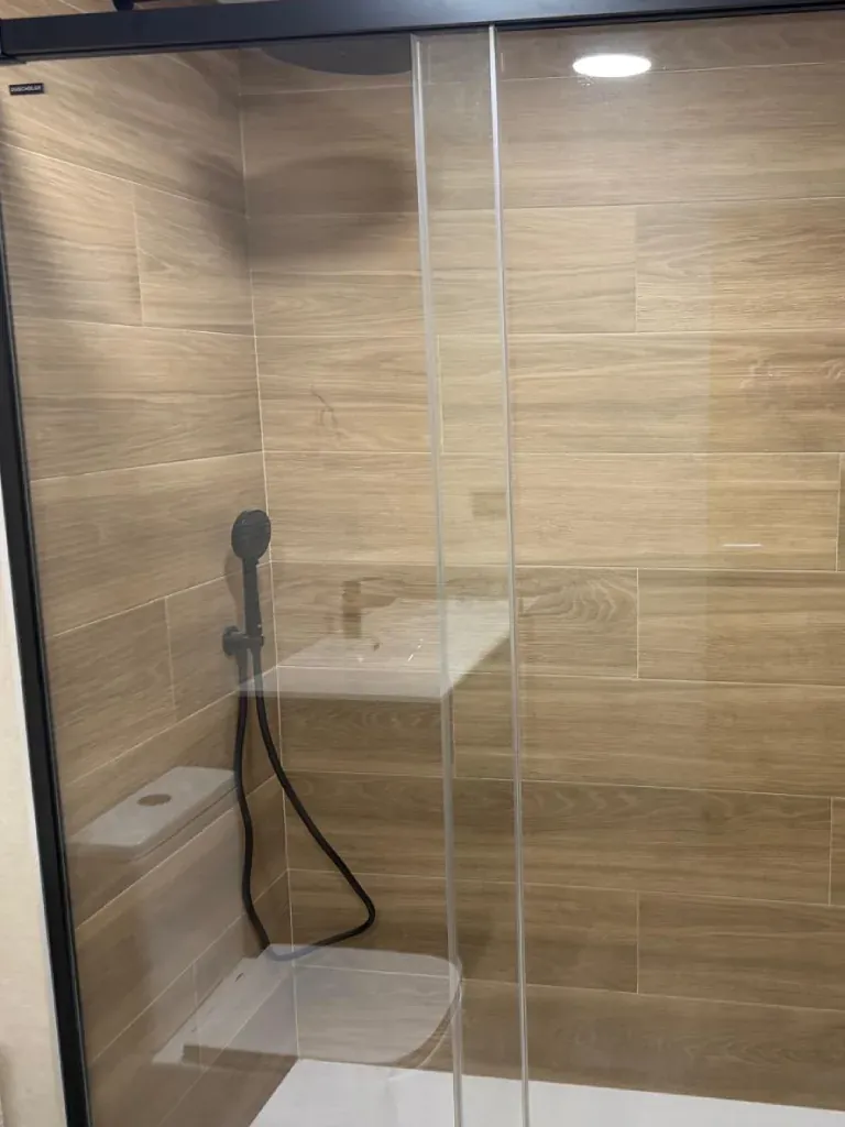 Ducha con mampara y alicatado imitación madera clara