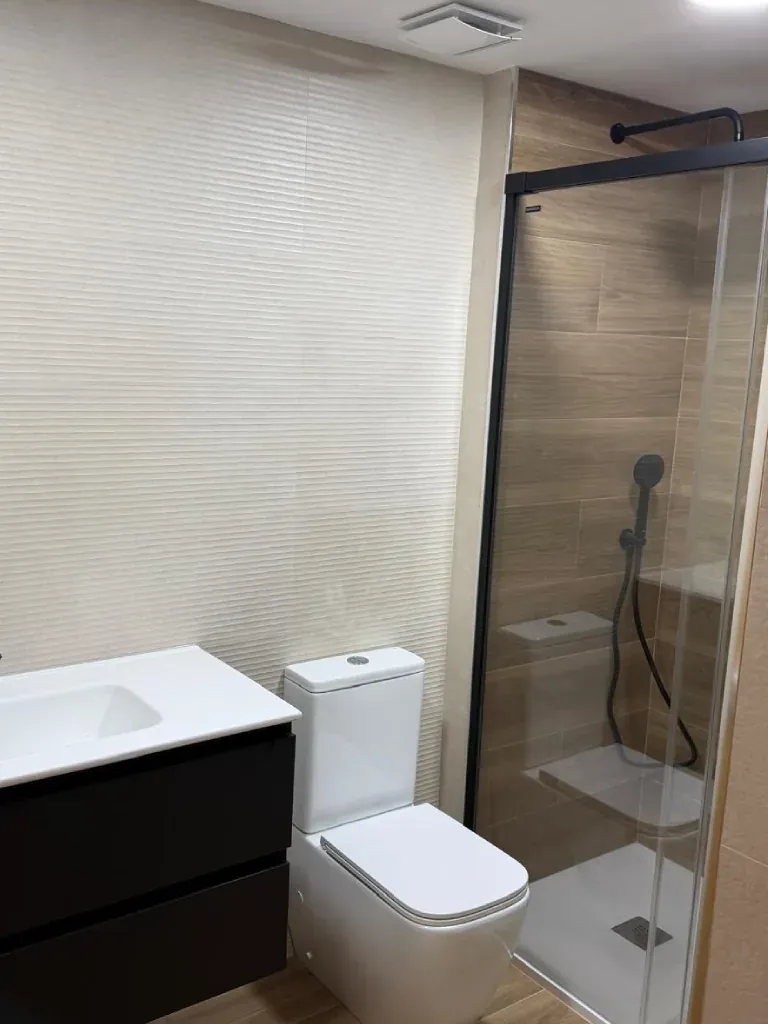 Baño reformado con mueble de baño negro y espejo LED