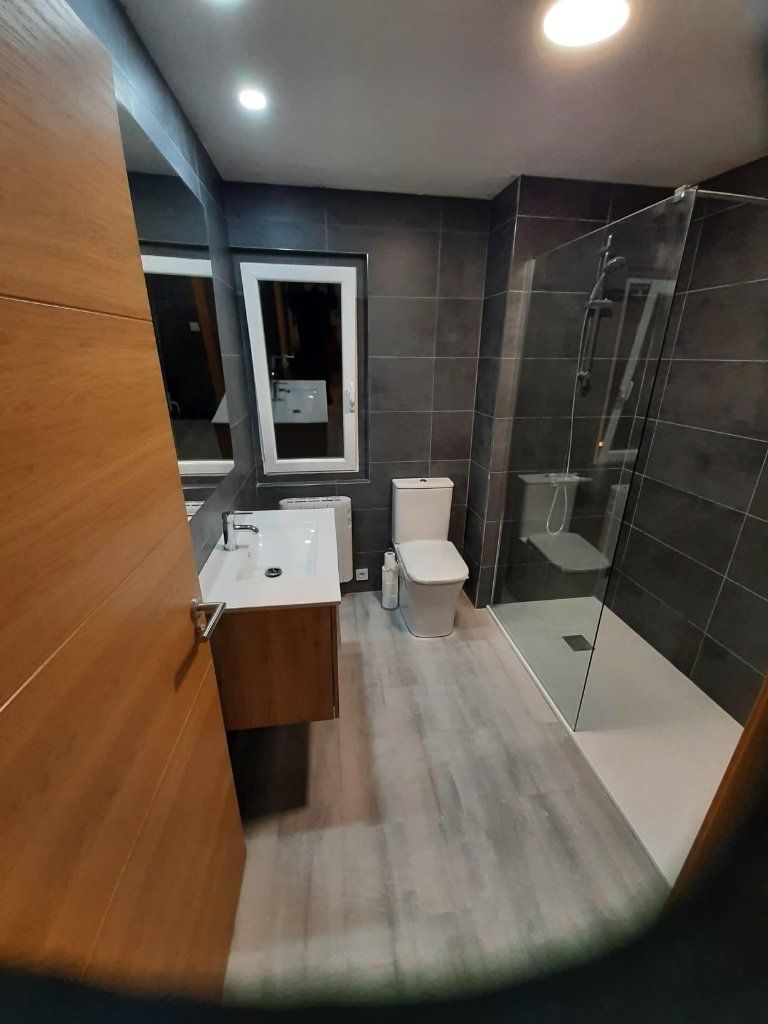 Baño reformado con mampara corredera y suelo laminado